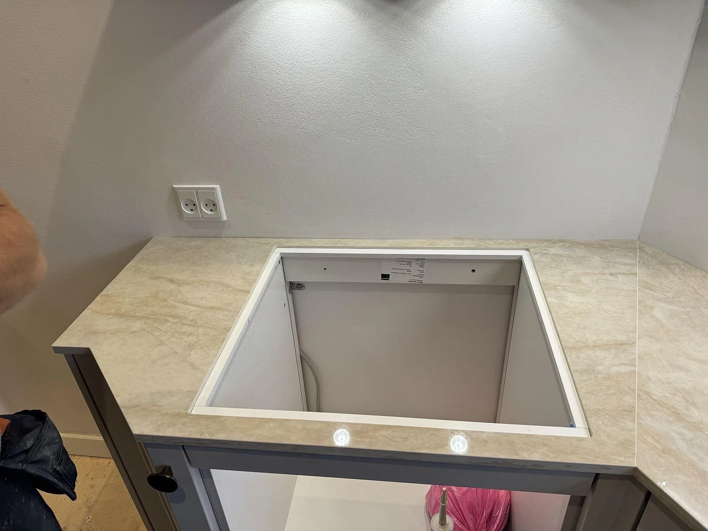Förberett urtag för häll i polerad Dekton Arga köksbänkskiva över öppna stommar under montering i København N.