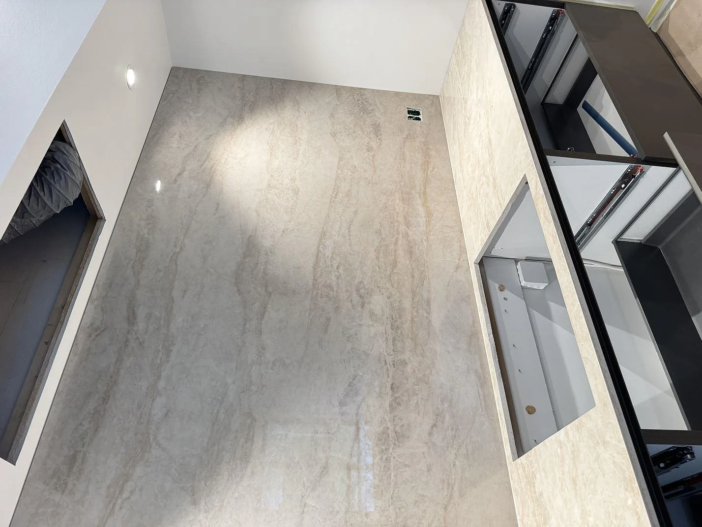 Översikt av väggbeklädnad och köksö i polerad Dekton Arga, med öppna köksstommar under montering i Köpenhamn S.
