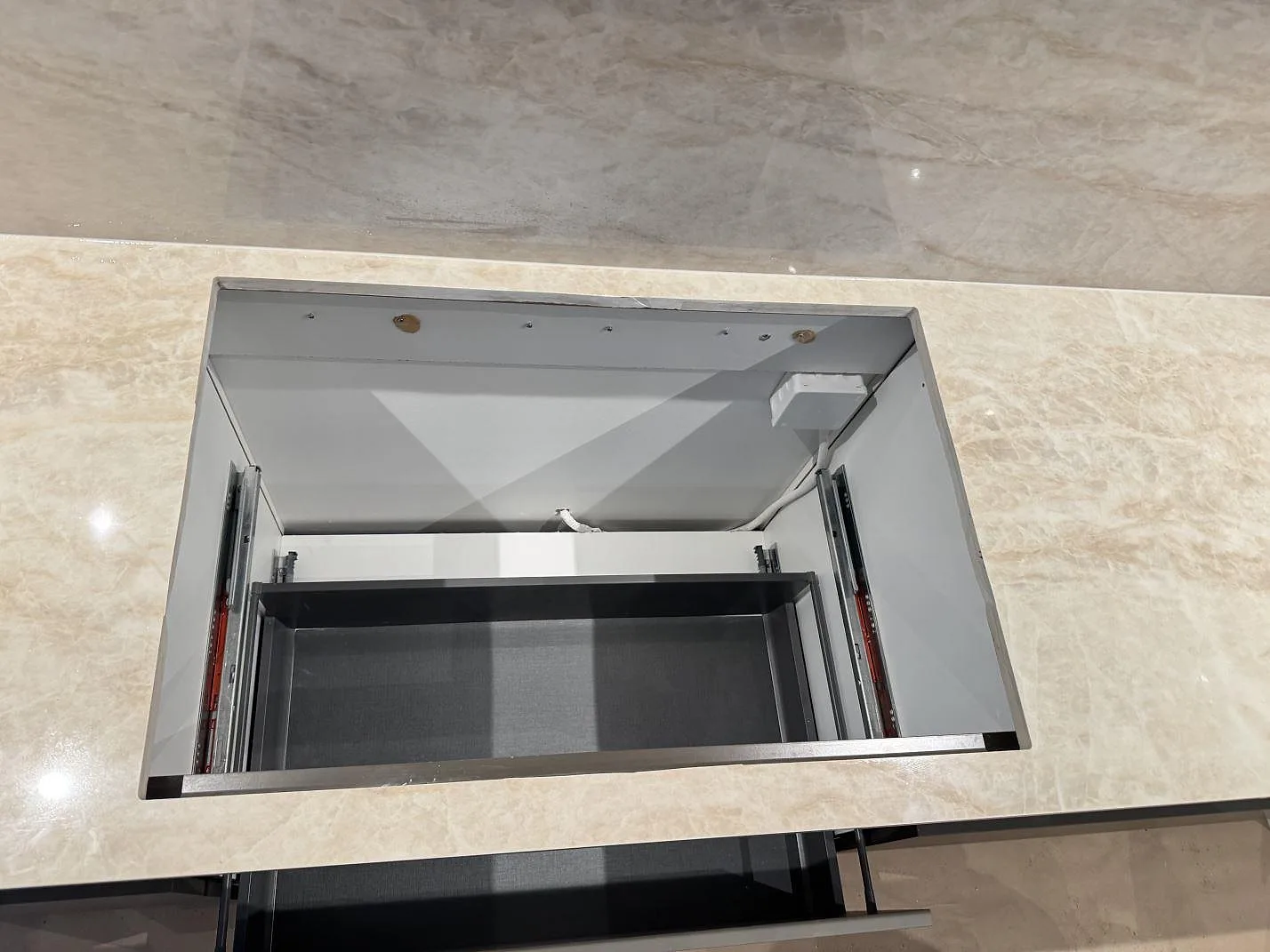 Ovanifrån på bearbetat urtag i polerad Dekton Arga, cremebeige keramik, med väggbeklädnad i samma sten bakom i Köpenhamn S.