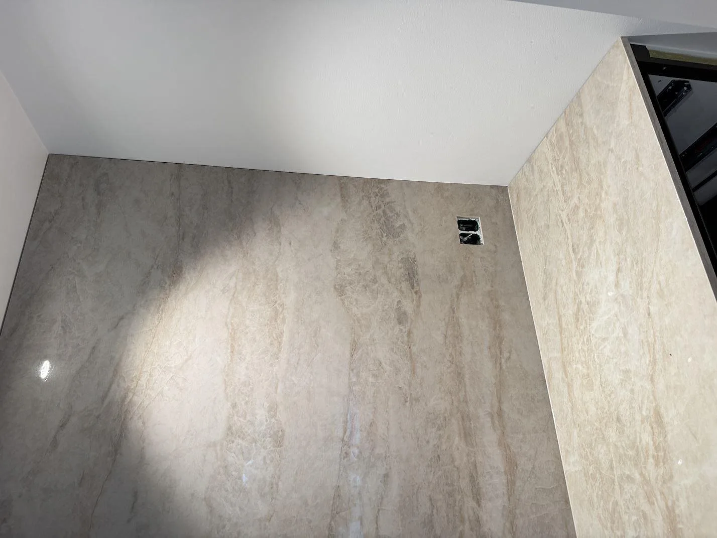 Polerad Dekton Arga som väggbeklädnad med varm ådring och sidostycke i samma keramik vid en köksö i Köpenhamn S.