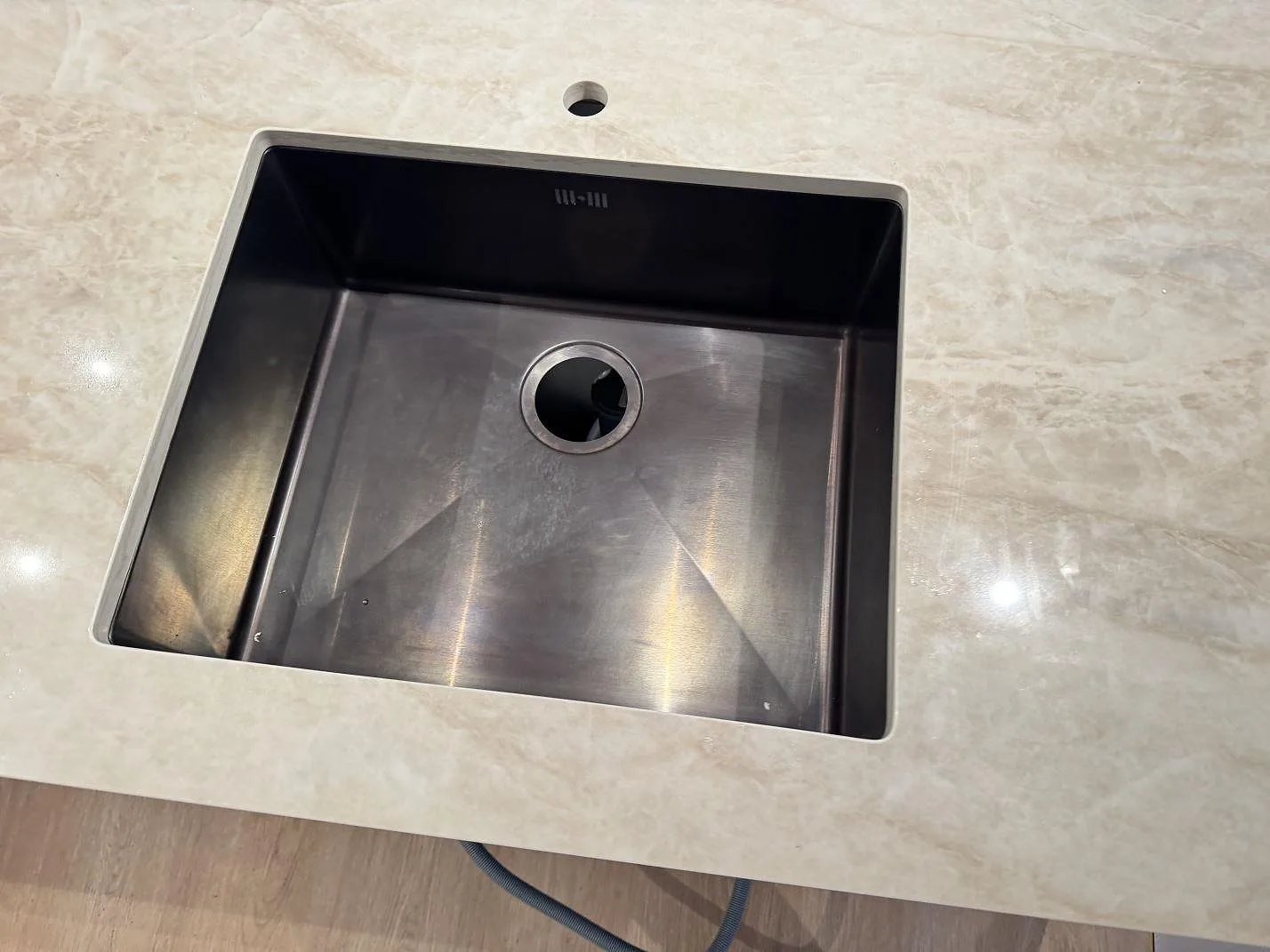 Detalj av rektangulärt urtag i en polerad köksbänkskiva av Dekton Arga med rund genomföring i ett kök i Köpenhamn S.