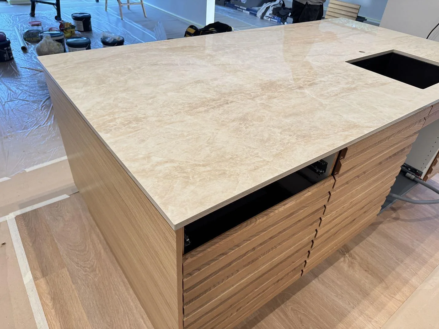 Köksö med köksbänkskiva i polerad Dekton Arga, cremebeige keramik, med rektangulärt urtag och träinredning i ett kök i Köpenhamn S.