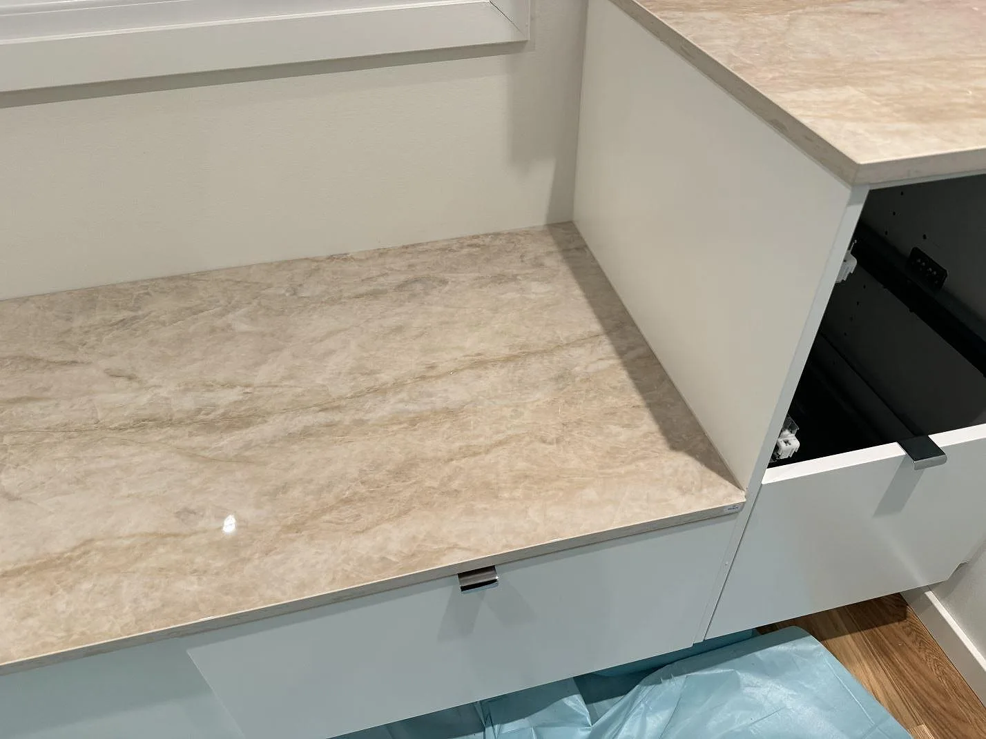 Detalj av polerad Dekton Arga på L-formad bänkskiva vid fönster och vit köksinredning i Kristianstad.