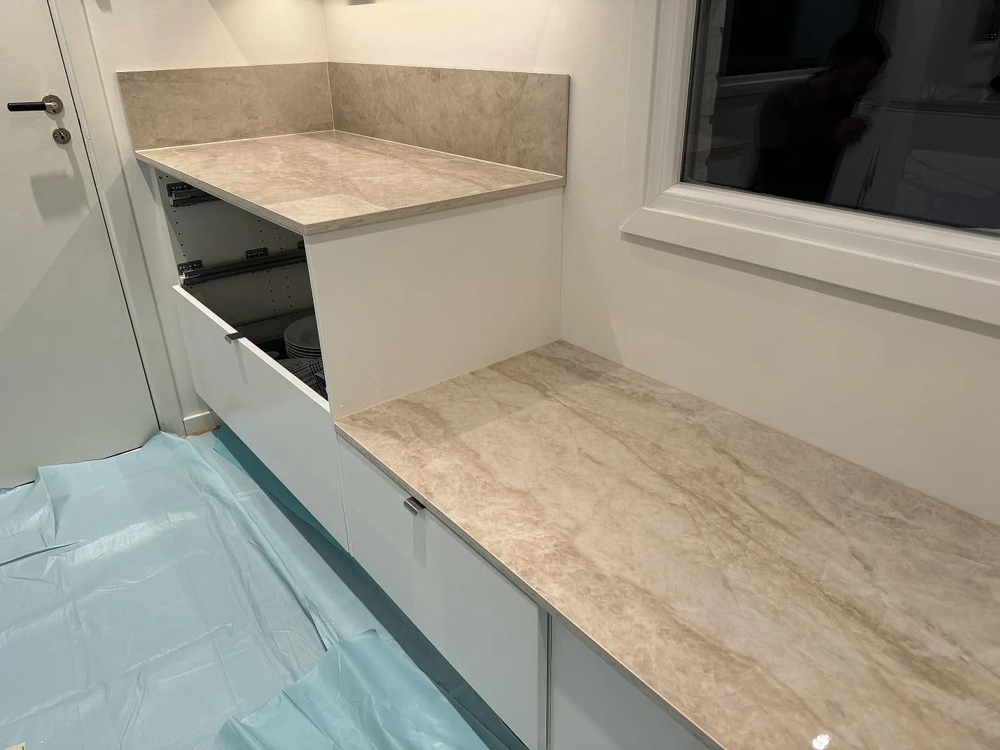 L-format kök med polerad Dekton Arga på bänkskiva, köksö och stänkskydd under montering i Kristianstad.