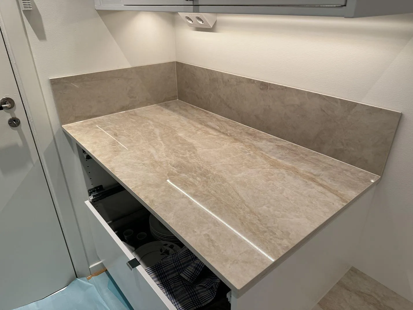 Polerad Dekton Arga med uppvikt stänkskydd ovanför vit köksinredning i Kristianstad.