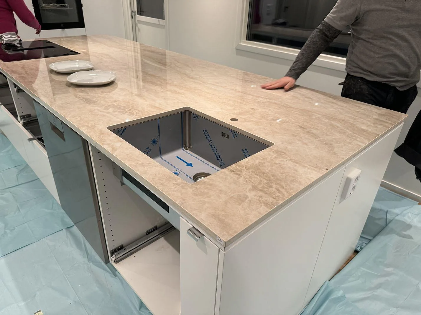 Polerad köksbänkskiva i Dekton Arga på vit köksö med underlimmad diskho och induktionshäll i Kristianstad.