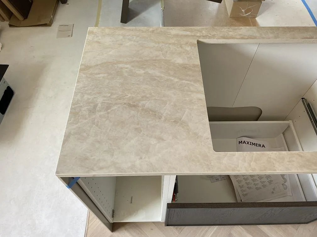 Köksö i polerad Dekton Arga keramik med stort öppet urtag och ljus marmorerad ådring under montering i Kristianstad.