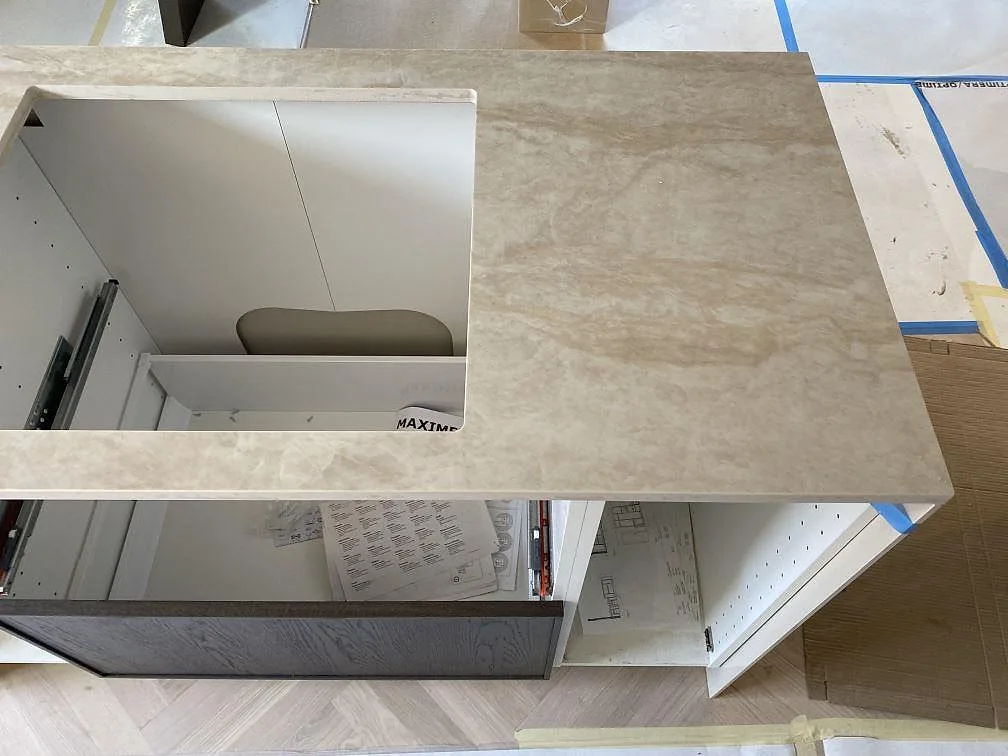 Detalj av köksö i polerad Dekton Arga med stort urtag, öppna stommar och ljus marmorerad yta i Kristianstad.
