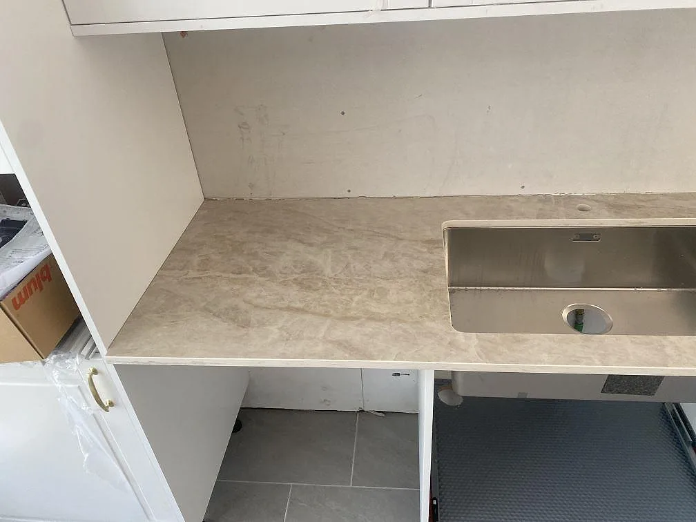 Närbild på underlimmad rostfri diskho i ljus Dekton Arga köksbänkskiva med marmorlik ådring i ett kök i Landvetter.