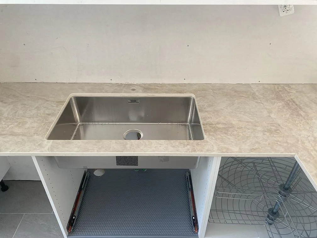 Underlimmad rostfri diskho i polerad Dekton Arga köksbänkskiva i ett kök i Landvetter, sedd i ögonhöjd.