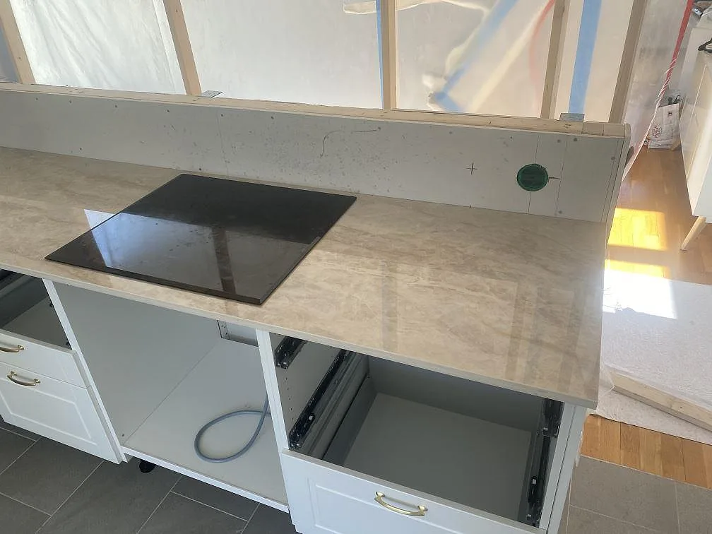 Polerad Dekton Arga köksbänkskiva i Landvetter med infälld svart induktionshäll och blank yta som speglar rummet.