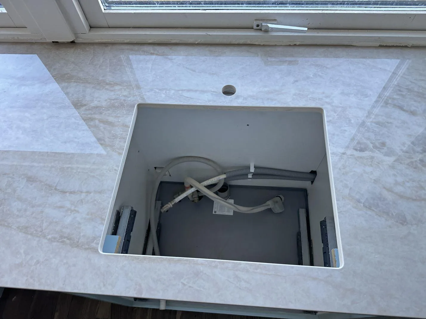 Detalj av öppet urtag i polerad Dekton Arga, keramik, under monteringen av köksbänkskivan i Limhamn.