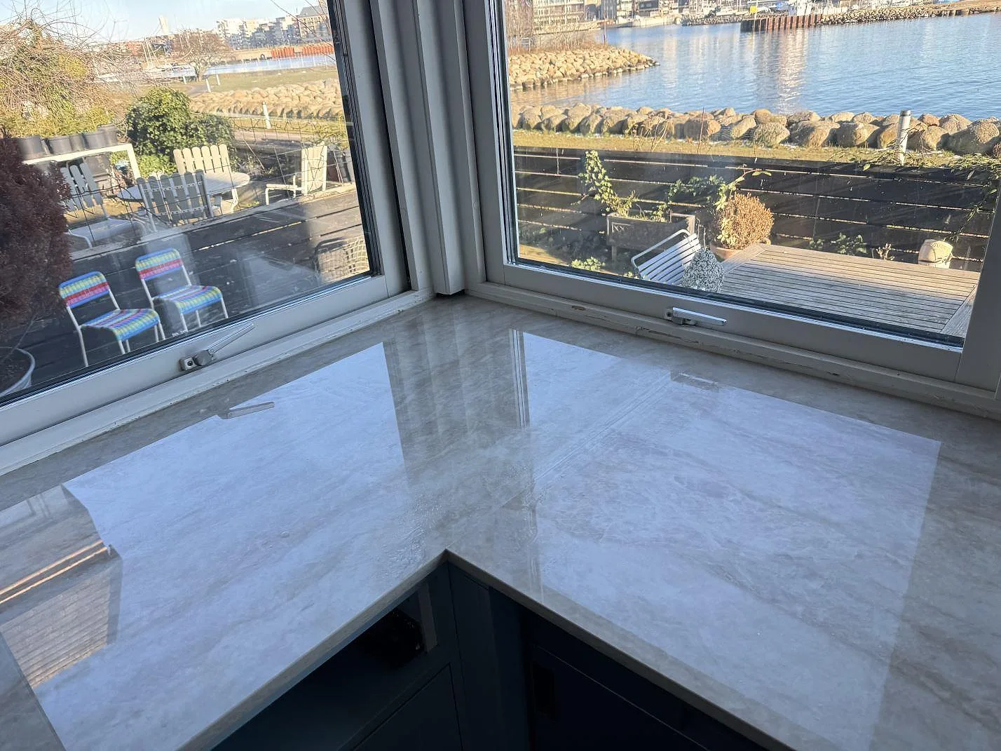 Hörnsektion av köksbänkskiva i polerad Dekton Arga med blank yta och marmorerad ådring vid fönster i Limhamn.