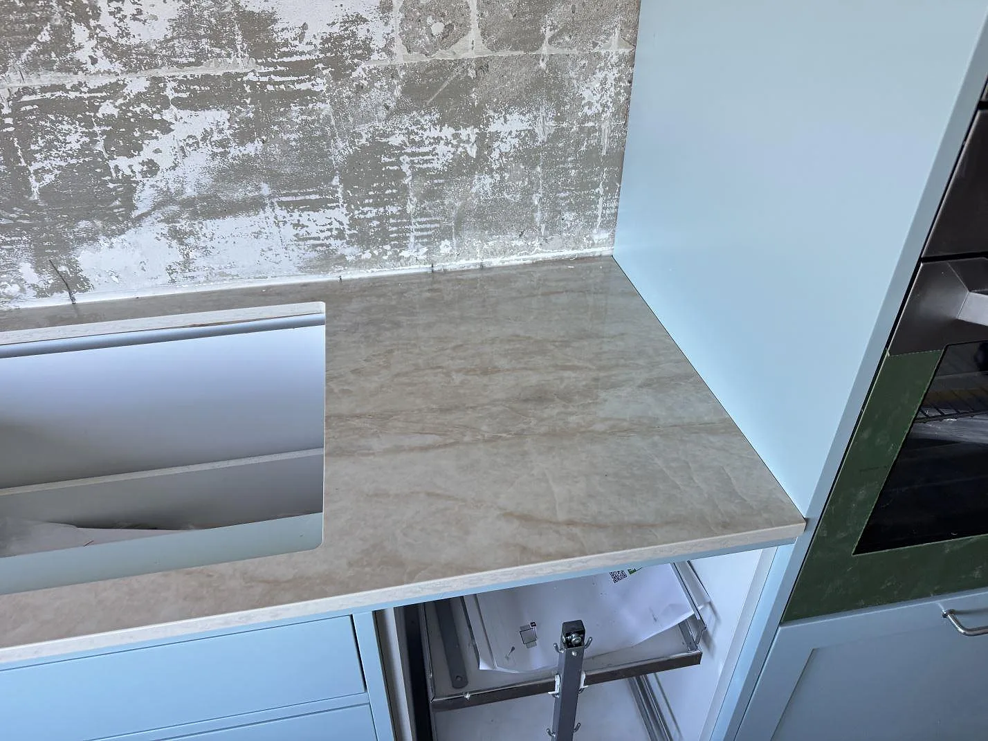 Köksbänkskiva i polerad Dekton Arga, keramik, med öppet urtag bredvid ugnsskåp i ett kök i Limhamn.