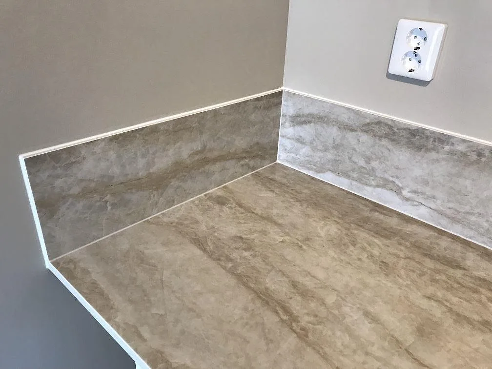 Köksbänkskiva i Dekton Arga, polerad keramik, med uppvikt stänkkant i samma sten i ett kök i Lomma.
