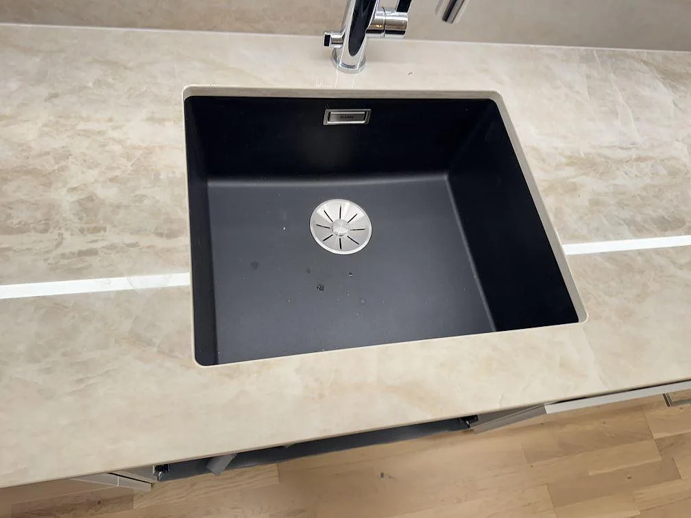 Närbild på svart diskho under polerad Dekton Arga keramik med beige ådring och blandare i Lomma.
