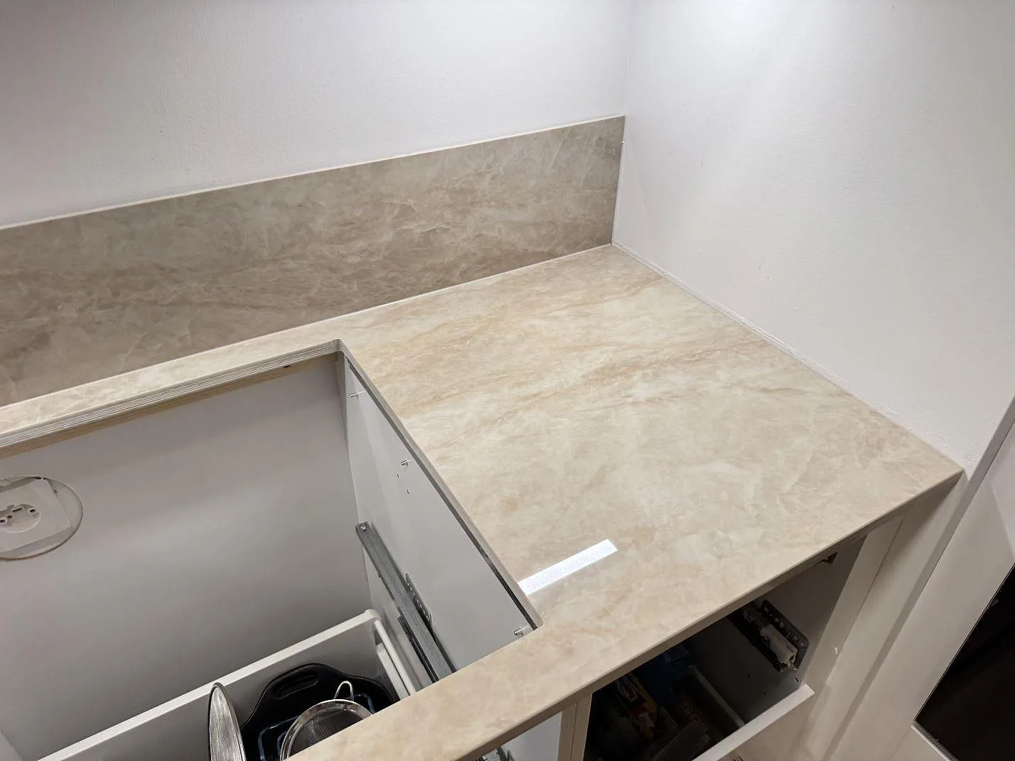 Hörnvy av polerad Dekton Arga keramik med öppet urtag och uppvikt stänkskydd i samma sten i Lomma.