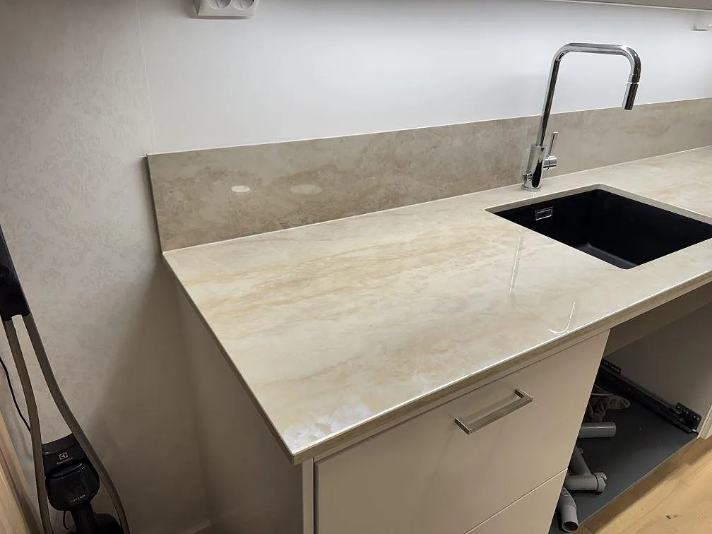 Vänster del av en polerad köksbänkskiva i Dekton Arga keramik med svart underlimmad diskho och stänkskydd i Lomma.