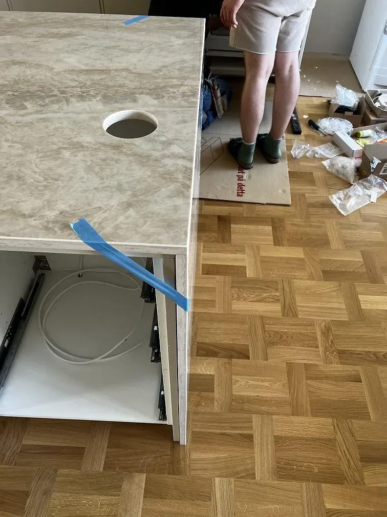 Detaljbild av Dekton Arga bänkdel i polerad keramik med rund öppning och synliga vita stommar under montering i Lund.