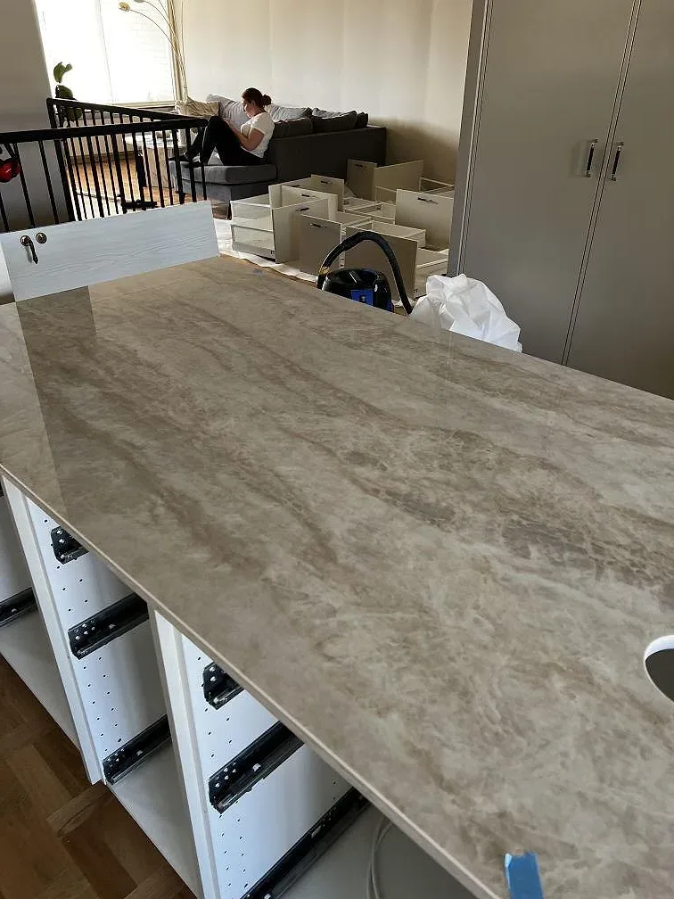 Närbild av polerad Dekton Arga keramik med beige ådring på bänkskiva och bänkdel i köket i Lund.