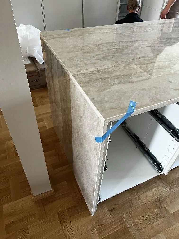 Sidovy av monterad Dekton Arga keramik med polerad kant, öppen köksstomme och parkettgolv i Lund.
