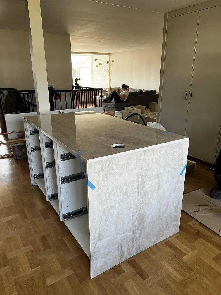 Polerad Dekton Arga keramik på en bänkdel med rund öppning, vita stommar och parkettgolv under montering i Lund.