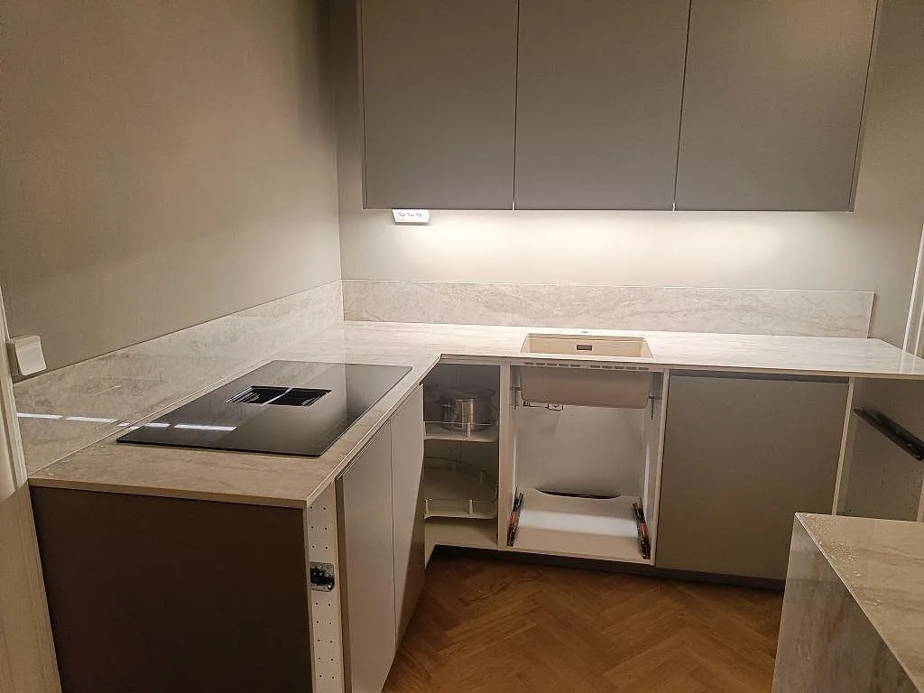 Köksbänkskiva i vit Dekton Arga, polerad, i ett U-format kök i Malmö med övermonterad induktionshäll och underlimmad diskho.