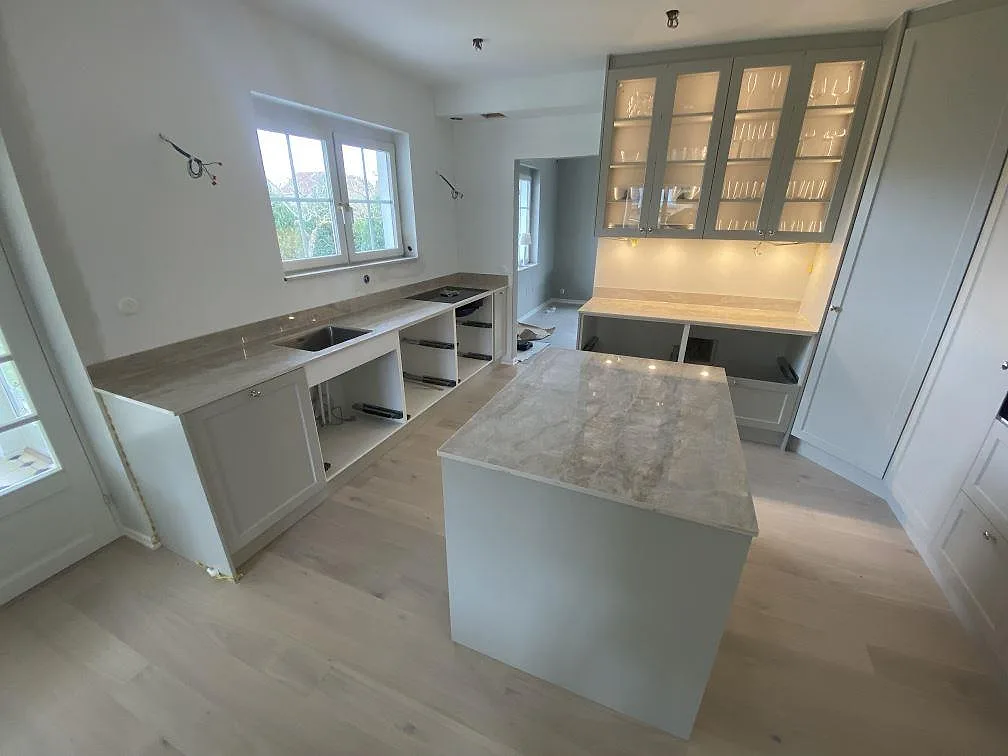 Köksbänkskiva och köksö i ljusgrå Dekton Arga, polerad, i ett kök under montering i Malmö.