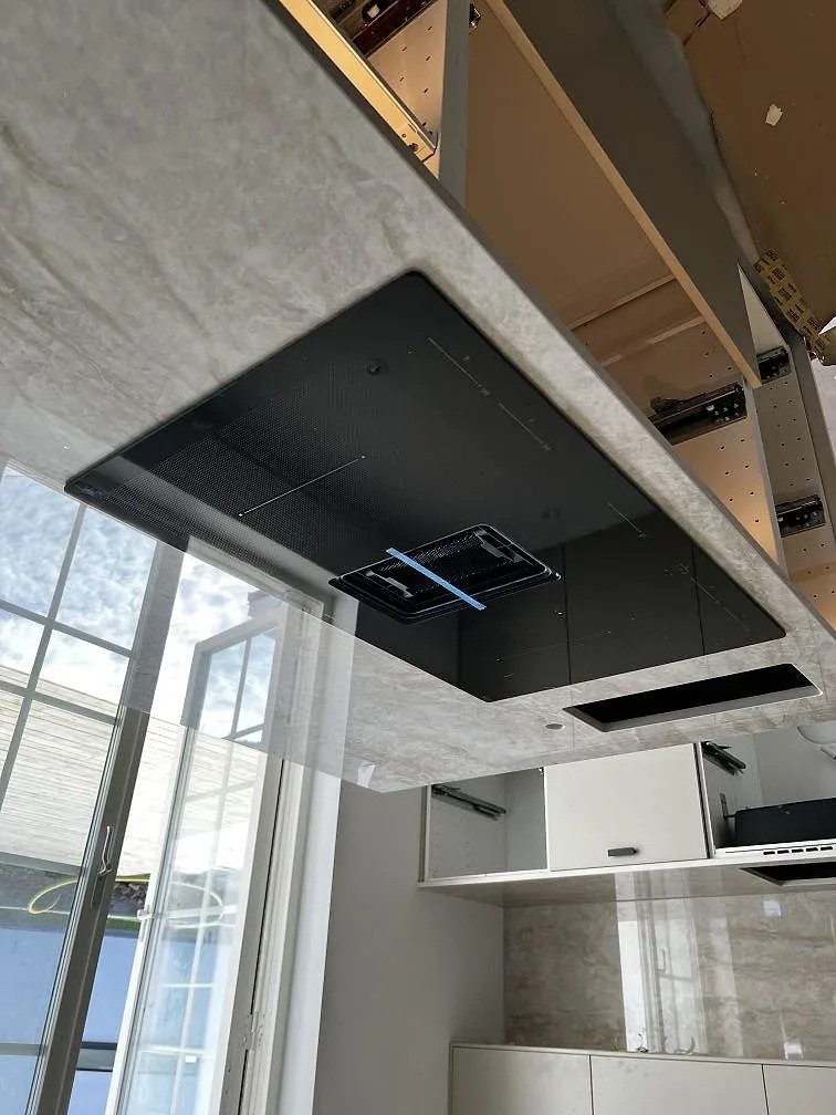 Köksö i Dekton Arga med infälld svart induktionshäll i ett ljust kök i Malmö.