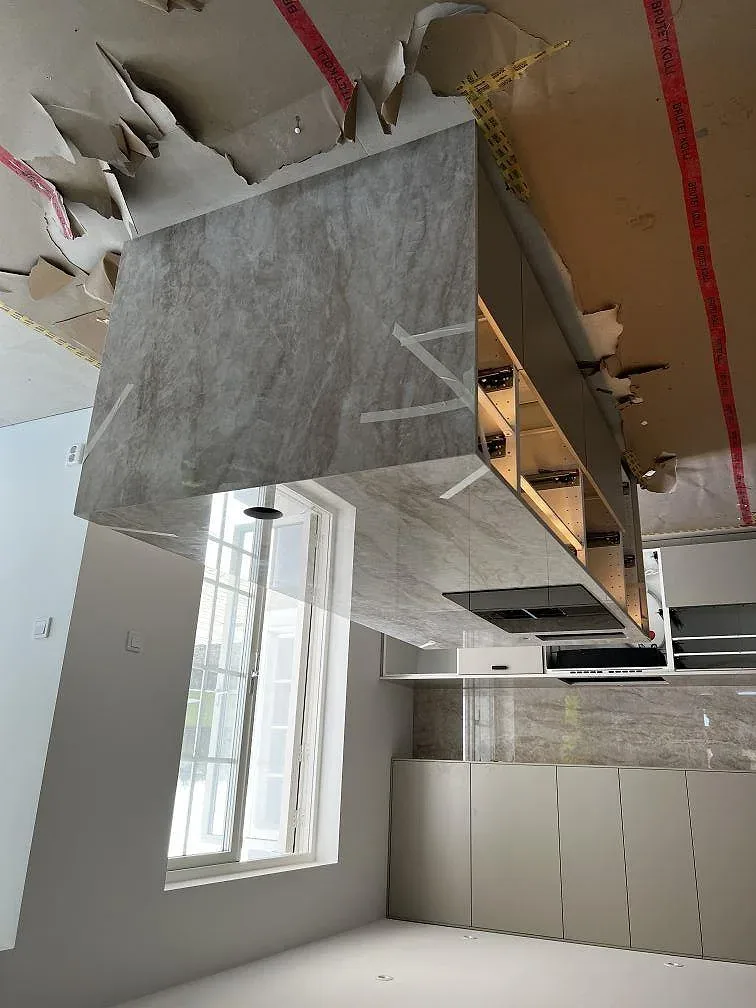 Stor köksö i ljust gråmelerad Dekton Arga med polerad yta och vattenfallssida i ett kök i Malmö.