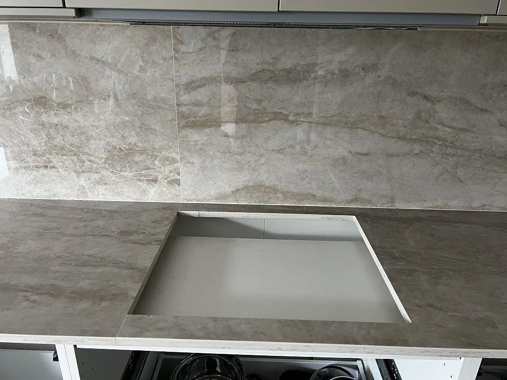Urtag för häll i polerad Dekton Arga med hög stänkvägg i samma keramik i ett kök i Malmö.