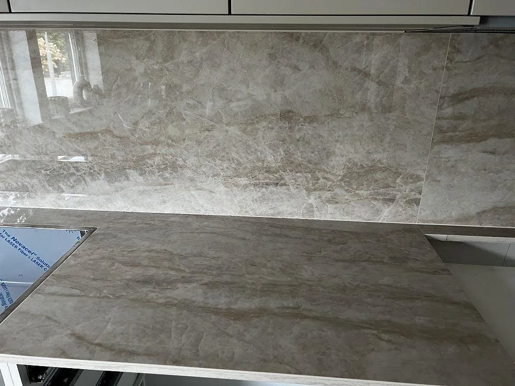 Detalj av polerad Dekton Arga som köksbänkskiva med hällplats, diskhoöppning och heltäckande stänkskydd i Malmö.