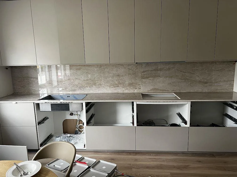 Köksbänkskiva i polerad Dekton Arga med heltäckande stänkskydd, svart diskho och hällplats i ett kök i Malmö.