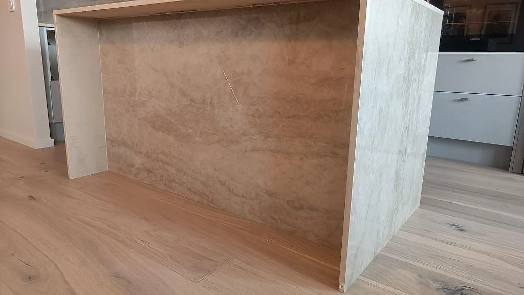 Närbild av vattenfallssida på köksö i polerad keramisk Dekton Arga med beige ådring i Malmö.