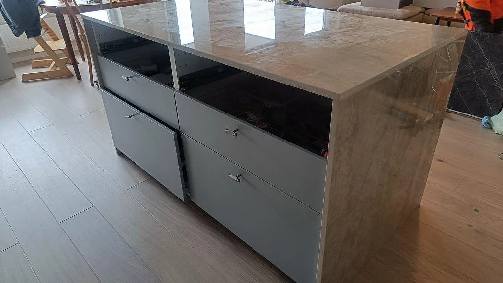 Polerad köksö i keramisk Dekton Arga med öppna lådstommar under montering i ett kök i Malmö.