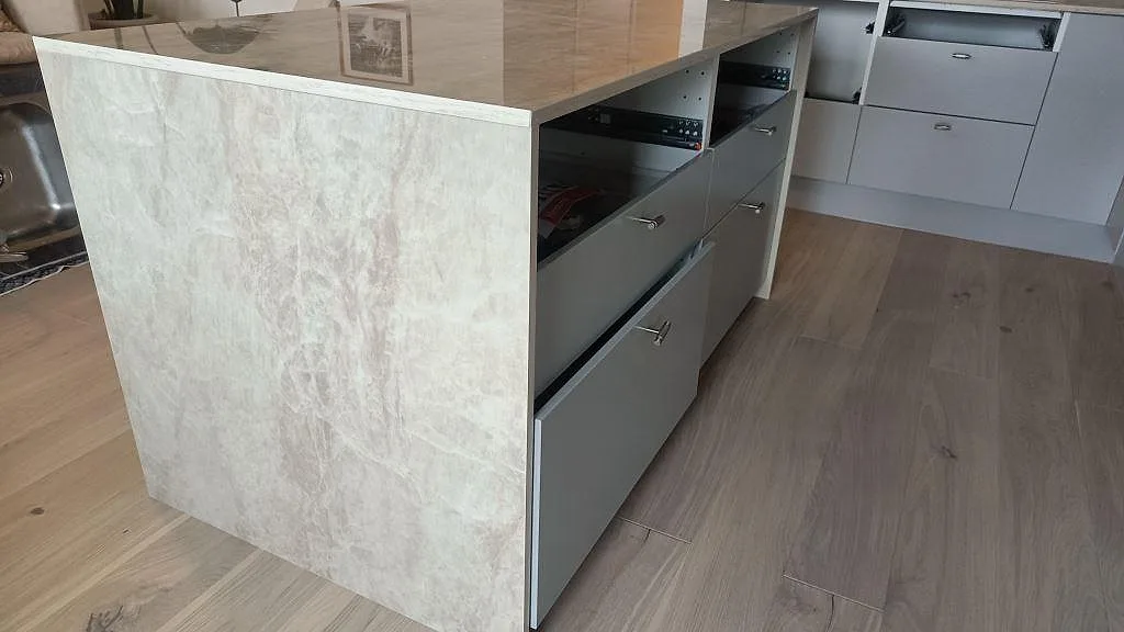 Vattenfallssida på köksö i polerad keramisk Dekton Arga med ljus ådring och vita köksstommar i Malmö.