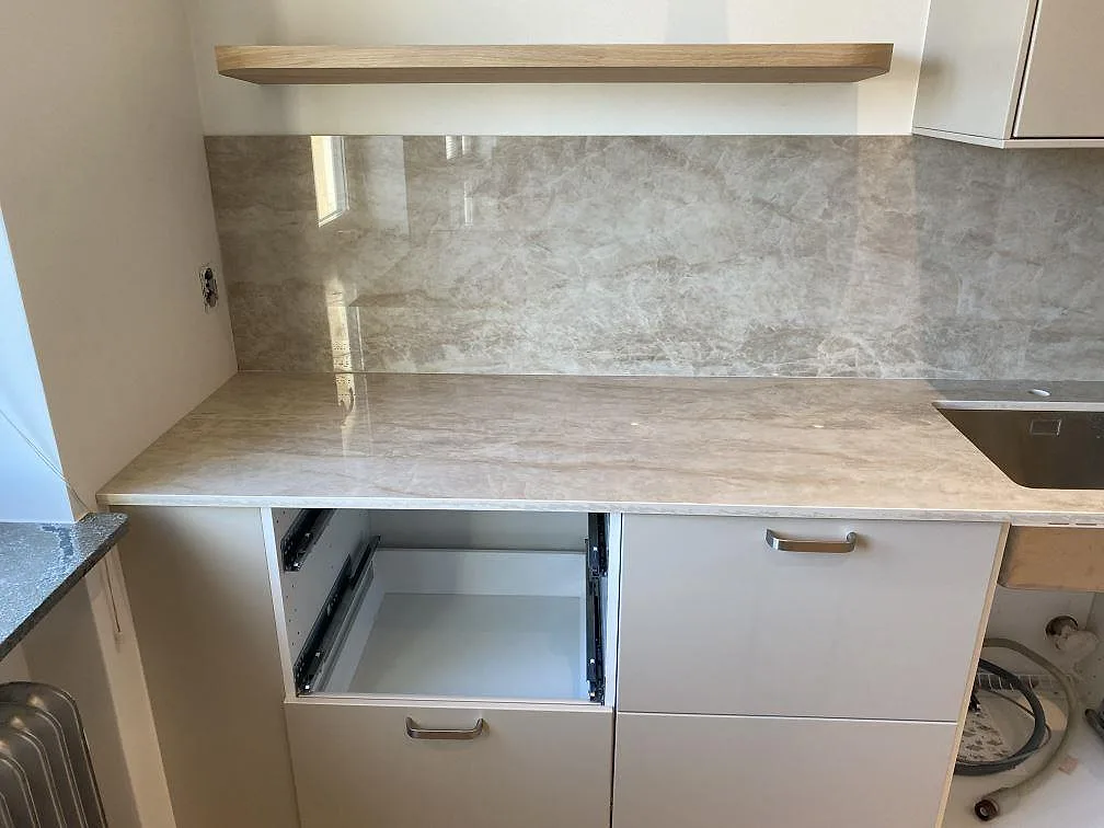 Bänkskiva i polerad Dekton Arga med matchande stänkskydd och synlig diskho i ett kök under montering i Malmö.