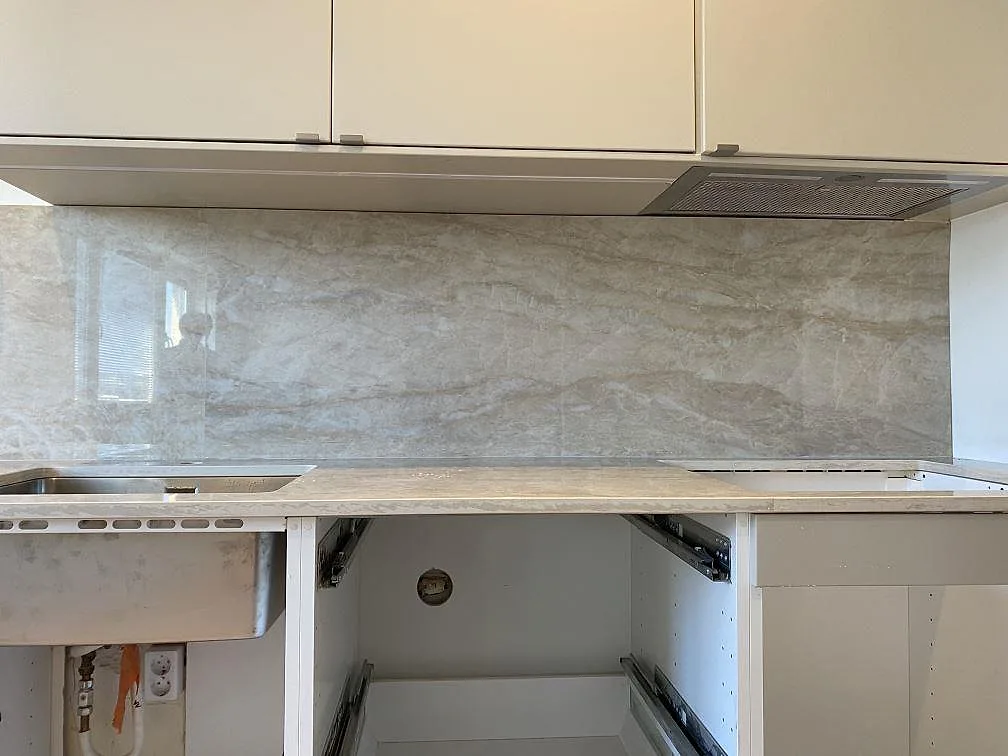 Stänkskydd och bänkskiva i polerad Dekton Arga längs arbetsväggen med diskho och hällöppning i Malmö.
