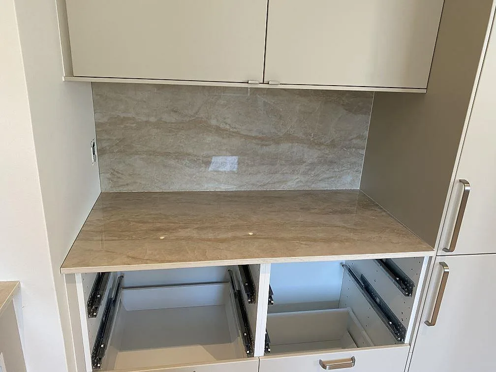 Rak arbetsyta i polerad Dekton Arga med stänkskydd mellan högskåp i ett kök i Malmö.