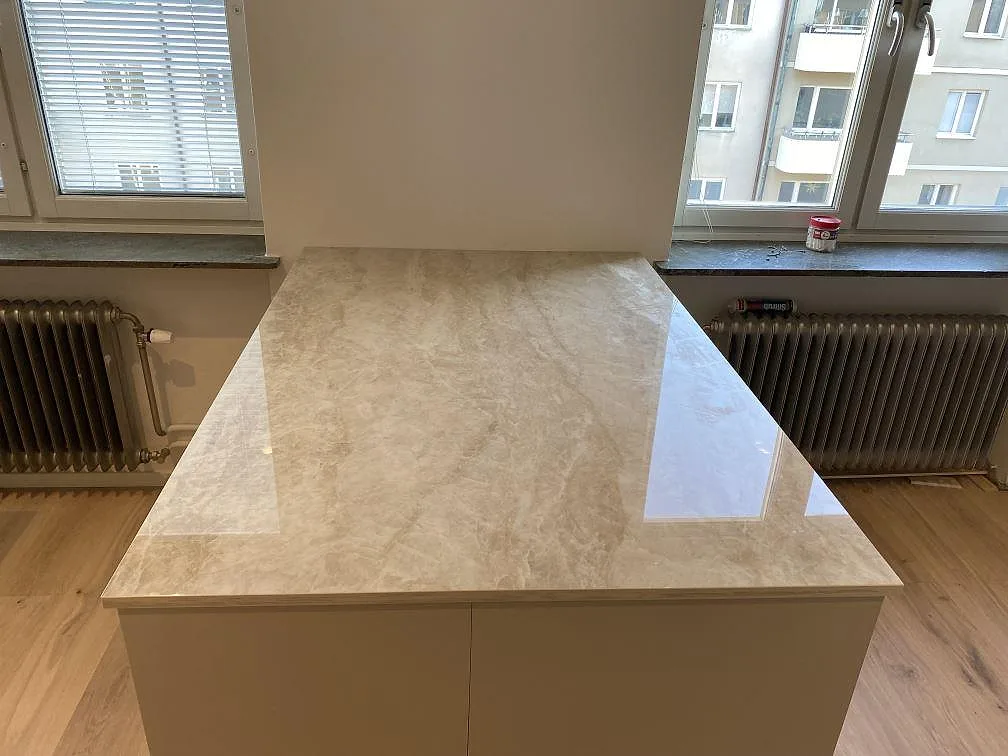 Bänkskiva på köksö i polerad Dekton Arga med ljus ådring framför fönster i Malmö.