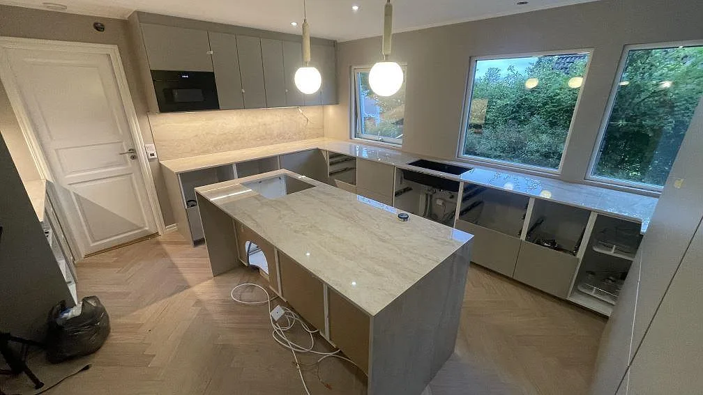 Översikt av kök i Malmö med köksö, väggbänkar och stänkskydd i polerad Dekton Arga keramik.