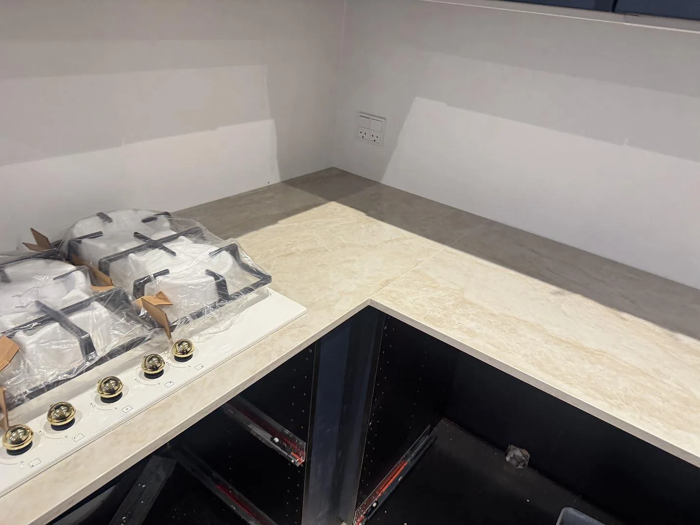 Hörnparti med köksbänkskiva i Dekton Arga och gashäll, fotat under montering i ett kök i Marstal på Ærø.