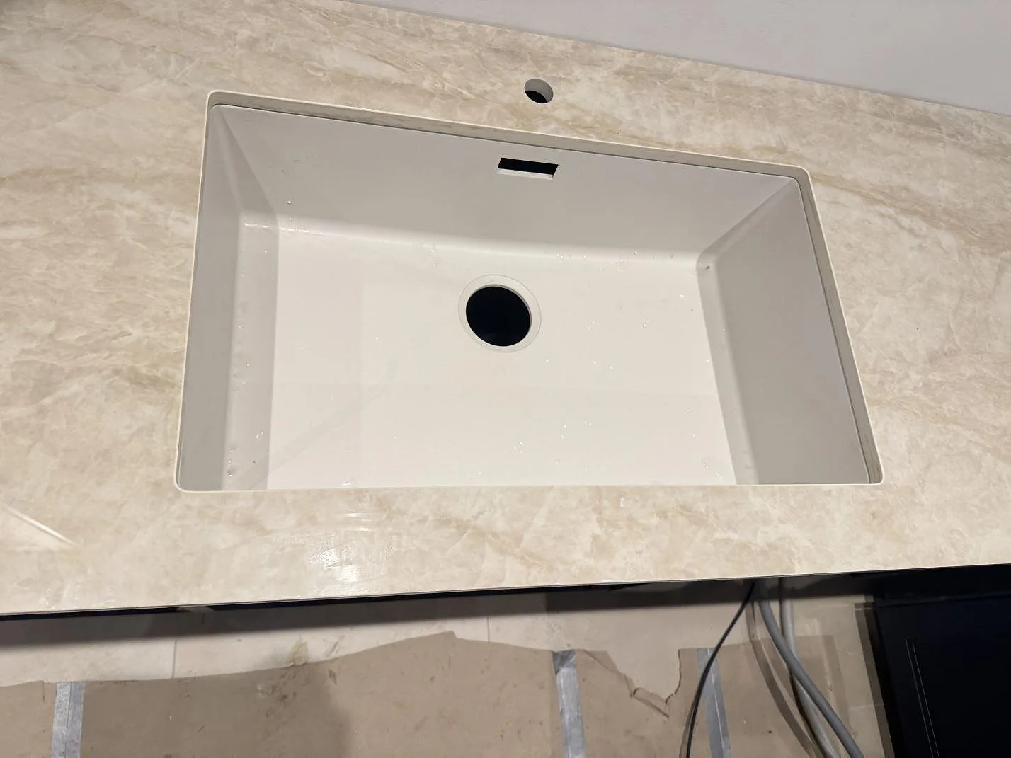 Vit underlimmad diskho infälld i en polerad Dekton Arga köksbänkskiva med mjuk beige ådring i ett kök i Marstal på Ærø.