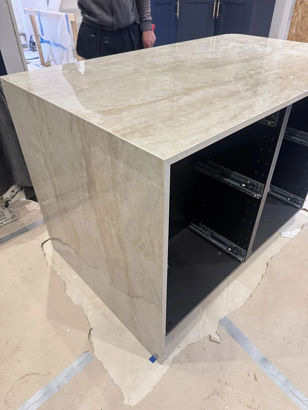Fristående köksö i Dekton Arga med vattenfallskant och öppna lådstommar under montering i ett kök i Marstal på Ærø.