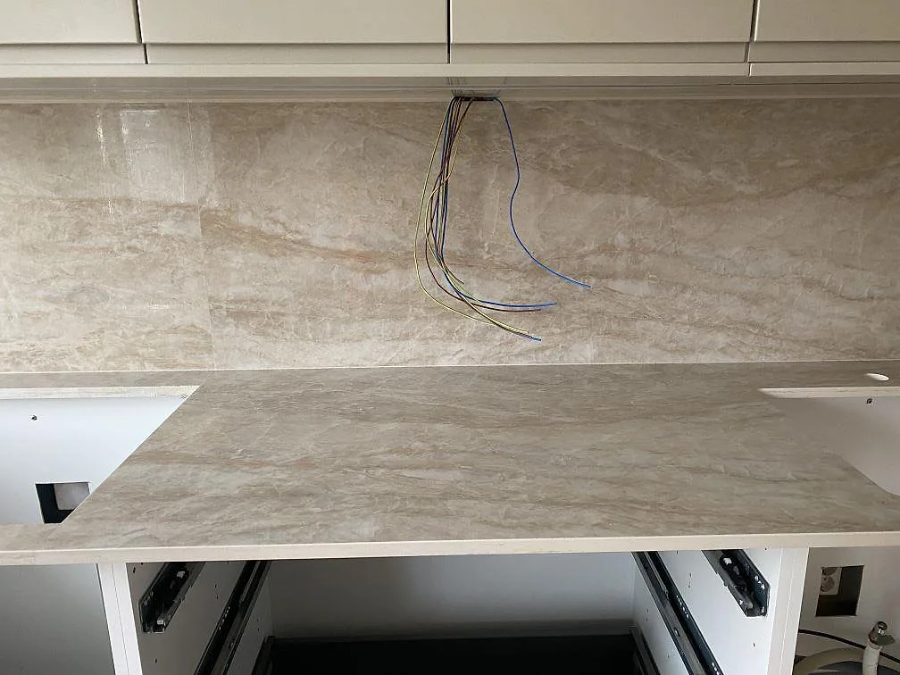 Närbild på ljus ådring i polerad Dekton Arga köksbänkskiva och stänkskydd i ett kök i Mölndal.