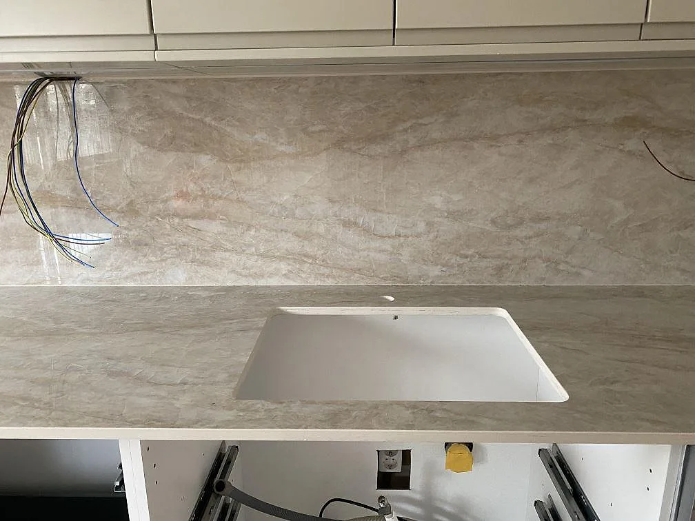 Polerad köksbänkskiva i Dekton Arga med underlimmad diskho och uppvikt polerat stänkskydd i ett kök i Mölndal, fotat under montering.