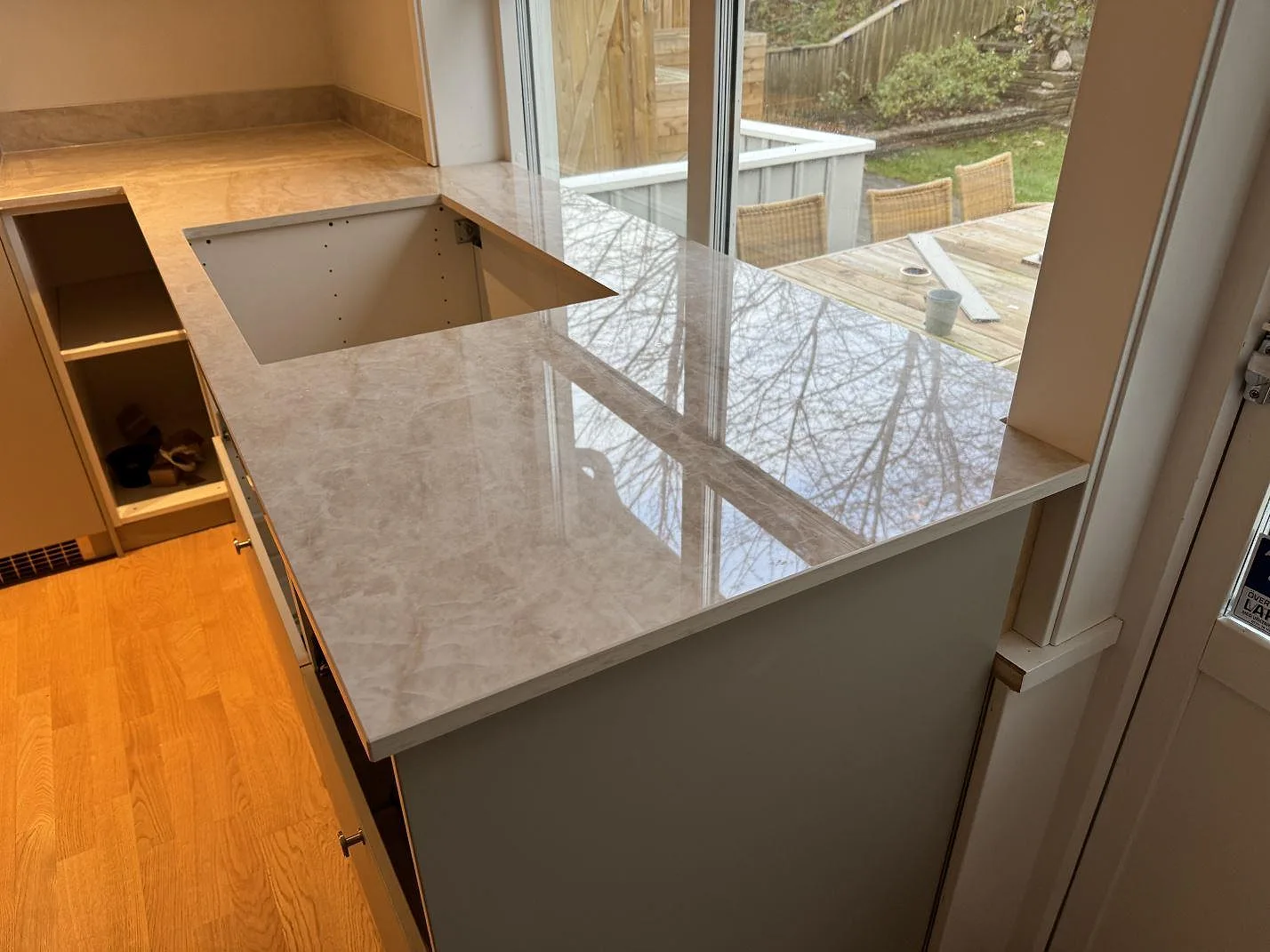 Köksbänkskiva i polerad Dekton Arga, 20 mm keramik, med L-formad bänk och halvö framför stora fönster i Mölndal.