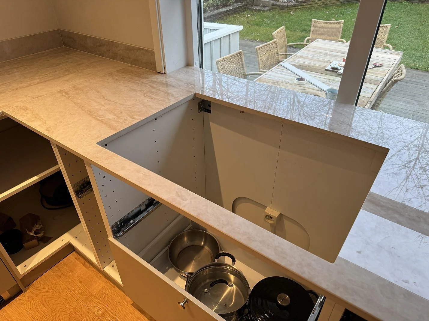 Polerad Dekton Arga köksbänkskiva vid stora fönster, med vit stomme och öppna lådor under montering i Mölndal.