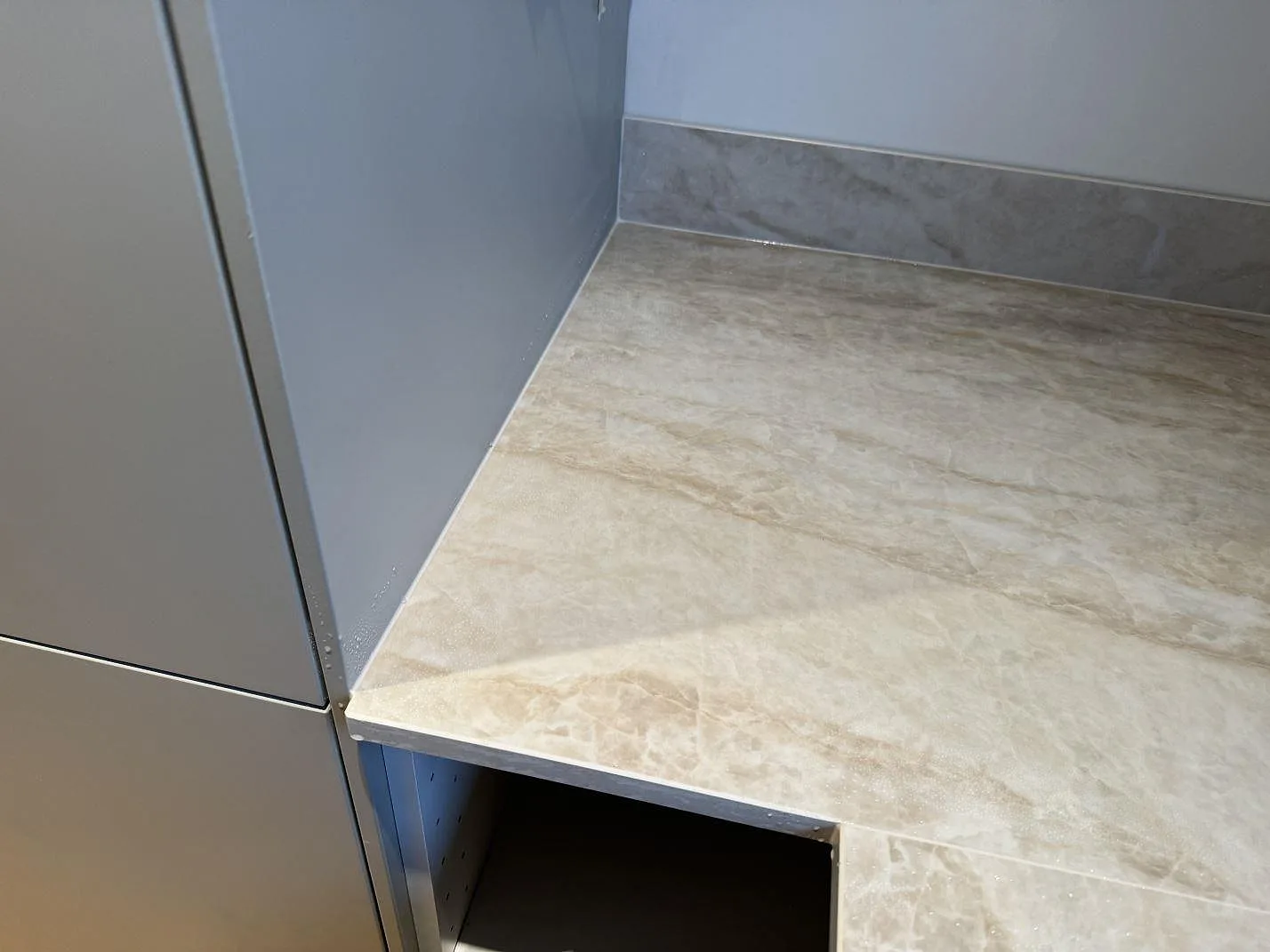 Närbild på polerad Dekton Arga bänkskiva vid högskåp, med fasad kant och matchande stänkskydd i Mölndal.