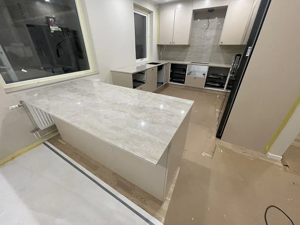 Polerad köksbänkskiva i keramik, Dekton Arga, med bred arbetsyta och matchande väggbeklädnad i ett kök i Norrköping.